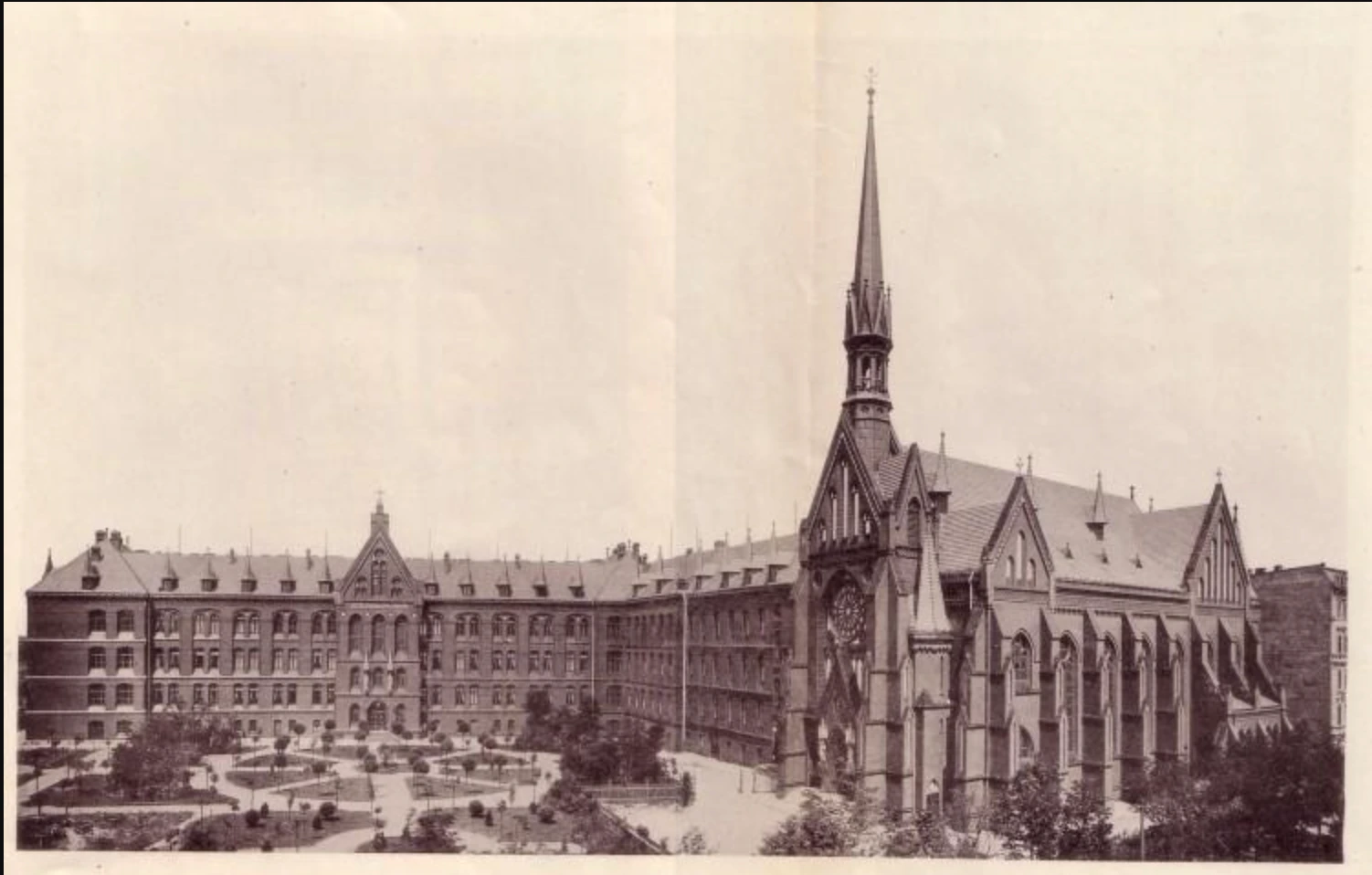 The hospital not long after it opened: brick wings around a garden, and the church at its corner. Period postcard, early 1900s.